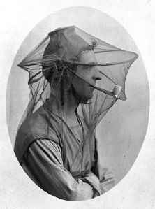L0011629 Postcard: mosquito net to be worn as a veil.